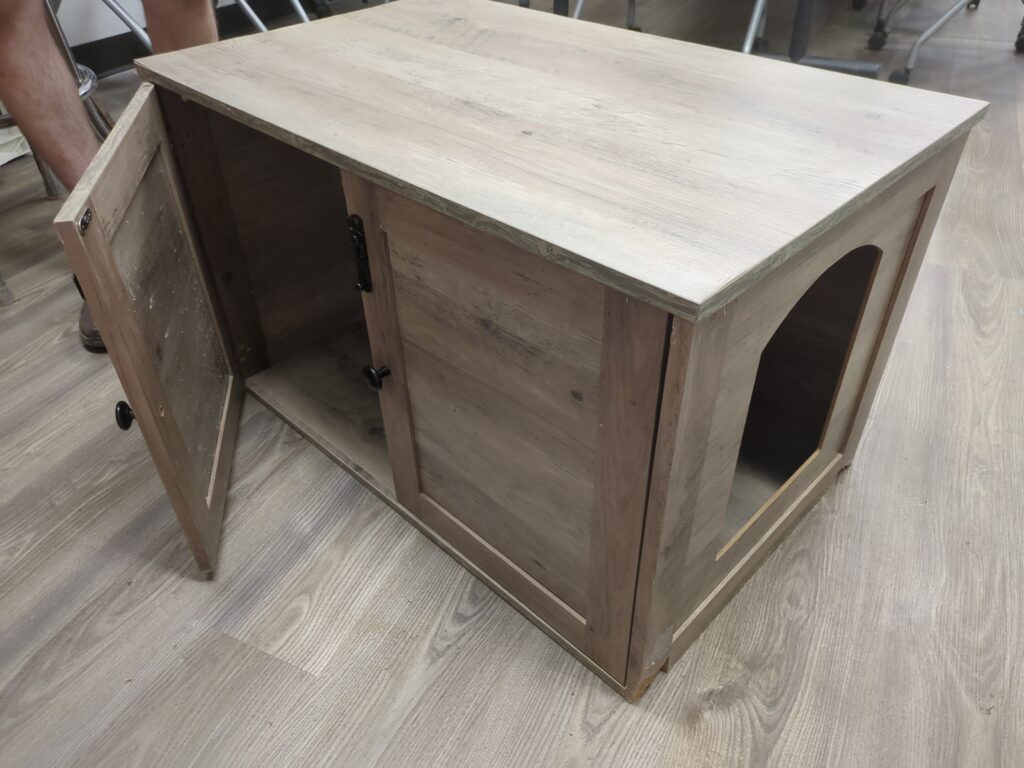 An enclosed coffee table with doors that swing open and a large cutout in one end for a cat to go into.