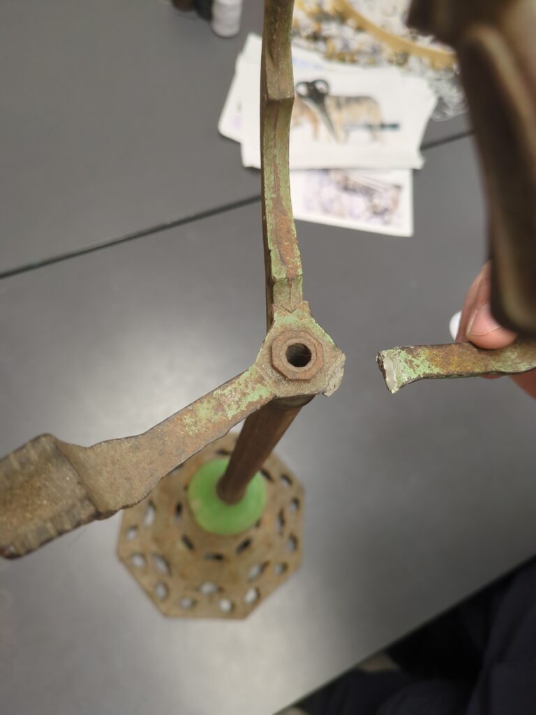 A metal stand with three prongs to hold an ashtray. One of the prongs is broken off.